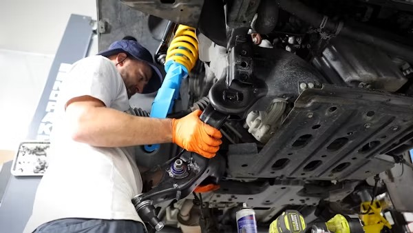 Technician replacing suspension strut on a vehicle