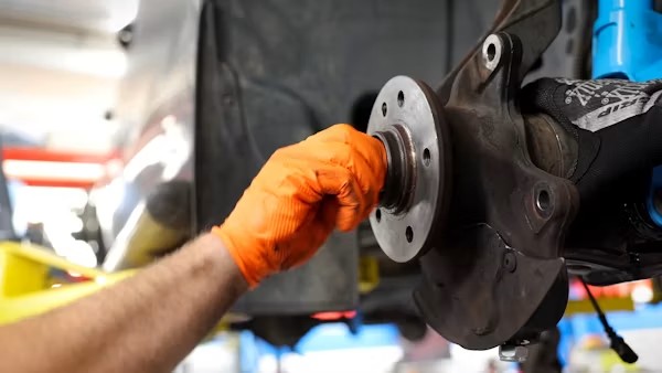 Mechanic checking brake pads during car inspection California